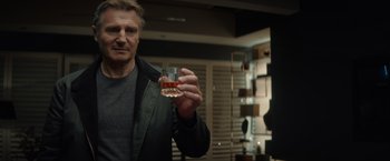 Movie still from “Blacklight” (2022), directed by Mark Williams – A man holding a shot glass in his hand; Close Up shot, Over the shoulder angle