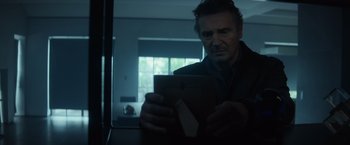 Movie still from “Blacklight” (2022), directed by Mark Williams – A man looking at a tablet computer in a dark room; Close Up shot, Low angle