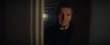 Movie still from “Blacklight” (2022), directed by Mark Williams – A man in a black shirt is looking at the camera; Close Up shot, Low angle