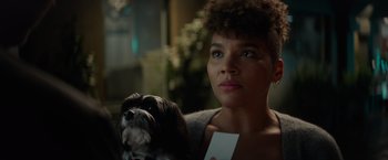 Movie still from “Blacklight” (2022), directed by Mark Williams – A woman holding a card and a small dog; Close Up shot, Over the shoulder angle
