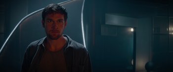 Movie still from “Blacklight” (2022), directed by Mark Williams – A young man standing in a dark room; Close Up shot, Low angle