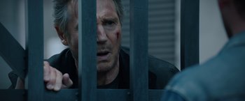 Movie still from “Blacklight” (2022), directed by Mark Williams – A man in a jail cell looking through a fence; Close Up shot, Over the shoulder angle