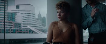 Movie still from “Blacklight” (2022), directed by Mark Williams – A woman sitting in front of a large window; Medium shot, Low angle