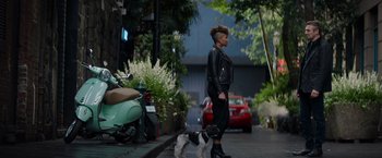 Movie still from “Blacklight” (2022), directed by Mark Williams – A woman walking a dog down a street; Wide shot, Low angle