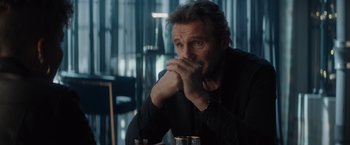 Movie still from “Blacklight” (2022), directed by Mark Williams – A man sitting at a table with his hand under his chin; Close Up shot, Over the shoulder angle