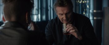 Movie still from “Blacklight” (2022), directed by Mark Williams – A man holding a can of beer while sitting down; Close Up shot, Over the shoulder angle