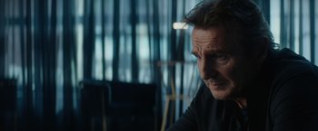 Movie still from “Blacklight” (2022), directed by Mark Williams – A person sitting at a table; Close Up shot, Over the shoulder angle