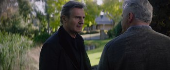 Movie still from “Blacklight” (2022), directed by Mark Williams – A person wearing a suit and tie; Close Up shot, Over the shoulder angle