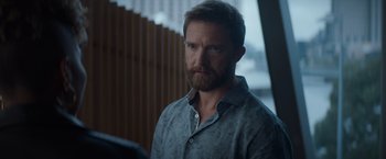 Movie still from “Blacklight” (2022), directed by Mark Williams – A man with a goatee is looking at the camera; Close Up shot, Over the shoulder angle