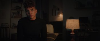 Movie still from “Blacklight” (2022), directed by Mark Williams – A woman sitting on a chair in a dark room; Close Up shot, Over the shoulder angle