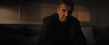 Movie still from “Blacklight” (2022), directed by Mark Williams – A person wearing a jacket; Close Up shot, Over the shoulder angle