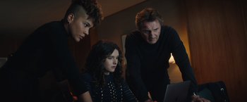 Movie still from “Blacklight” (2022), directed by Mark Williams – A group of young people looking at a laptop together; Medium shot, Low angle