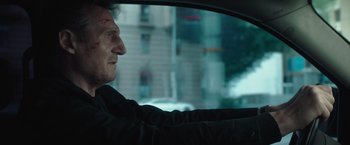 Movie still from “Blacklight” (2022), directed by Mark Williams – A man sitting in the driver's seat of a car looking out the window; Close Up shot, Low angle