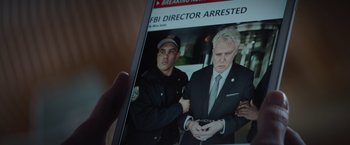 Movie still from “Blacklight” (2022), directed by Mark Williams – A person holding a magazine with a picture of a man and a police officer; Extreme Close Up shot, Low angle