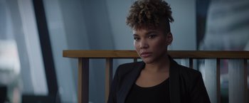 Movie still from “Blacklight” (2022), directed by Mark Williams – A woman sitting in front of a wooden chair; Close Up shot, Low angle