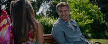 Movie still from “Blacklight” (2022), directed by Mark Williams – A man sitting on top of a bench next to a woman; Medium shot, Over the shoulder angle