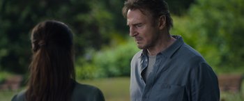 Movie still from “Blacklight” (2022), directed by Mark Williams – A man and a woman standing next to each other in a park; Close Up shot, Over the shoulder angle