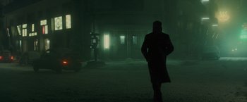 Movie still from “Blade Runner 2049” (2017), directed by Denis Villeneuve – A man in a coat and hat is standing in the fog; Wide shot, Low angle