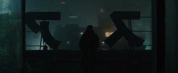Movie still from “Blade Runner 2049” (2017), directed by Denis Villeneuve – A person standing in front of a building at night; Extreme Wide shot, Low angle