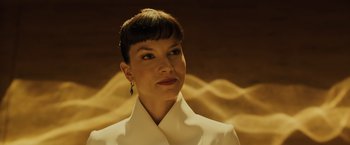 Movie still from “Blade Runner 2049” (2017), directed by Denis Villeneuve – A woman in a white jacket and a black and gold earring; Close Up shot, Low angle