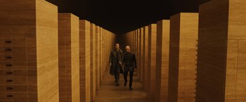 Movie still from “Blade Runner 2049” (2017), directed by Denis Villeneuve – Two men are walking down a long hallway of pillars; Wide shot, Low angle
