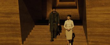 Movie still from “Blade Runner 2049” (2017), directed by Denis Villeneuve – A man and a woman are standing on some steps; Wide shot, Low angle