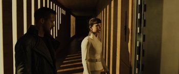 Movie still from “Blade Runner 2049” (2017), directed by Denis Villeneuve – A woman in a white suit standing next to a man in a white suit; Medium shot, Low angle