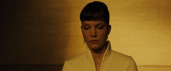 Movie still from “Blade Runner 2049” (2017), directed by Denis Villeneuve – A woman in a white jacket is looking down at her face; Close Up shot, Low angle