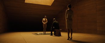 Movie still from “Blade Runner 2049” (2017), directed by Denis Villeneuve – A man sitting on the ground next to two women; Wide shot, High angle