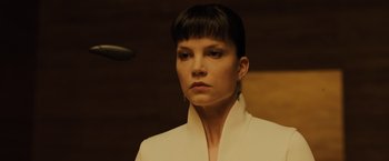 Movie still from “Blade Runner 2049” (2017), directed by Denis Villeneuve – A woman in a white jacket is looking at the camera; Close Up shot, Low angle