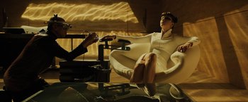 Movie still from “Blade Runner 2049” (2017), directed by Denis Villeneuve – A woman sitting on a chair in a room; Wide shot, High angle