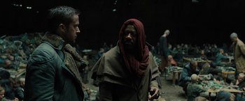 Movie still from “Blade Runner 2049” (2017), directed by Denis Villeneuve – A man with a beard is standing next to another man; Medium shot, Over the shoulder angle