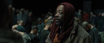 Movie still from “Blade Runner 2049” (2017), directed by Denis Villeneuve – An older man wearing a head scarf and a brown jacket; Close Up shot, Over the shoulder angle