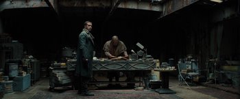 Movie still from “Blade Runner 2049” (2017), directed by Denis Villeneuve – Two men standing in front of a table; Medium shot, Low angle