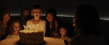 Movie still from “Blade Runner 2049” (2017), directed by Denis Villeneuve – A group of people standing around a cake with lit candles on it; Close Up shot, High angle