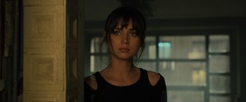 Movie still from “Blade Runner 2049” (2017), directed by Denis Villeneuve – A woman in a black shirt is standing in a room; Close Up shot, Over the shoulder angle