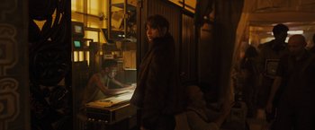 Movie still from “Blade Runner 2049” (2017), directed by Denis Villeneuve – A woman standing in front of a man in a dark room; Medium shot, Over the shoulder angle