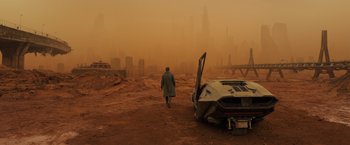 Movie still from “Blade Runner 2049” (2017), directed by Denis Villeneuve – A man walking down a dirt road near a car; Extreme Wide shot, High angle