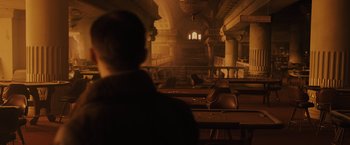 Movie still from “Blade Runner 2049” (2017), directed by Denis Villeneuve – A man standing in front of a large room with many chairs; Extreme Wide shot, High angle