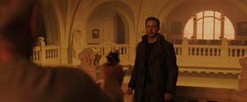 Movie still from “Blade Runner 2049” (2017), directed by Denis Villeneuve – A man standing in front of a camera in a room; Medium shot, Over the shoulder angle