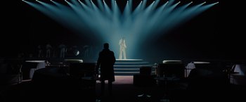 Movie still from “Blade Runner 2049” (2017), directed by Denis Villeneuve – A man standing in front of a stage with lights; Extreme Wide shot, Over the shoulder angle