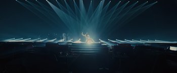 Movie still from “Blade Runner 2049” (2017), directed by Denis Villeneuve – A person is sitting on a stage in the middle of a show; Extreme Wide shot, High angle