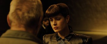 Movie still from “Blade Runner 2049” (2017), directed by Denis Villeneuve – A young woman with a short hair cut looks into the mirror; Close Up shot, Over the shoulder angle