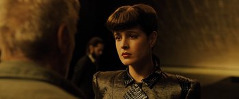 Movie still from “Blade Runner 2049” (2017), directed by Denis Villeneuve – A young woman with short brown hair wearing a black jacket; Close Up shot, Over the shoulder angle