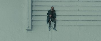 Movie still from “Blade Runner 2049” (2017), directed by Denis Villeneuve – A man sitting on the steps in the snow; Wide shot, Overhead angle