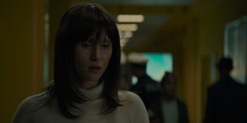 Movie still from “Blood Red Sky” (2021), directed by Peter Thorwarth – A woman in a white sweater standing next to a wall; Close Up shot, Over the shoulder angle