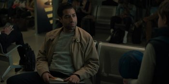 Movie still from “Blood Red Sky” (2021), directed by Peter Thorwarth – A man sitting on a bench holding a book in his hand; Medium shot, Over the shoulder angle