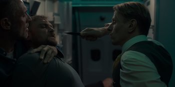 Movie still from “Blood Red Sky” (2021), directed by Peter Thorwarth – A man holding a knife up to another man's face; Medium shot, Over the shoulder angle