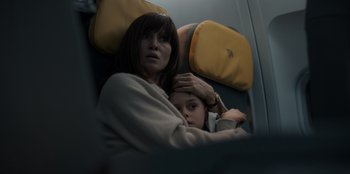 Movie still from “Blood Red Sky” (2021), directed by Peter Thorwarth – A woman sitting next to a young girl on a plane; Close Up shot, Overhead angle