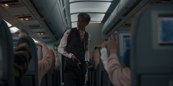 Movie still from “Blood Red Sky” (2021), directed by Peter Thorwarth – A man walking down the aisle of an airplane; Medium shot, Over the shoulder angle